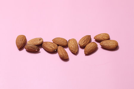 nuts almonds scattered on a pink background.の写真素材