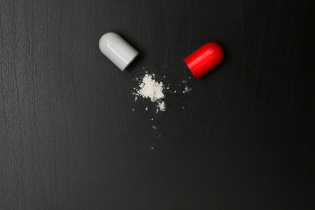 capsule with medicinal pill open powder sprinkling white medicinal active ingredient antibiotic on a...