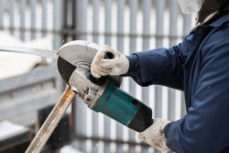 Working angle grinder in the hands of a worker. Gloves, sparks of metal.の写真素材