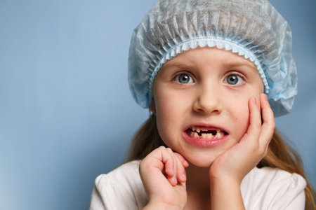 A little girl at the dentist shows a toothless mouth. Replacement of temporary teeth with permanent...