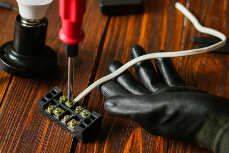 Electrician hands connecting wires in terminal block. Connection of wires with clamps. An...