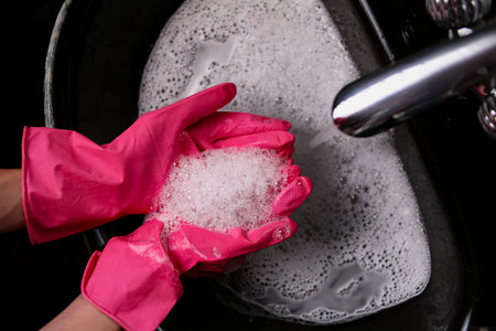 A lot of white foam from cleaning products in the black sink, cleaning the bathroom, cleaning ceramic surfaces with gloves.の写真素材