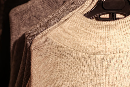 collection of beige and gray sweaters on hangers in a boutique
