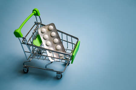 Pills in the basket. White pills, capsules in a trolley close-up. Concept of buying medicines online, delivery of medicines during an epidemic.の写真素材