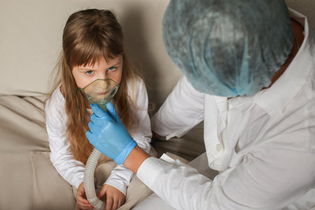 Young European doctor helping a little girl with a spray mask. Doctor applying inhalation medication therapy on little girl with inhalation therapy for asthma with inhaler mask.の写真素材