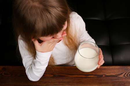 Child girl refuses to drink milk from a glass, covers her mouth with her hand.の写真素材