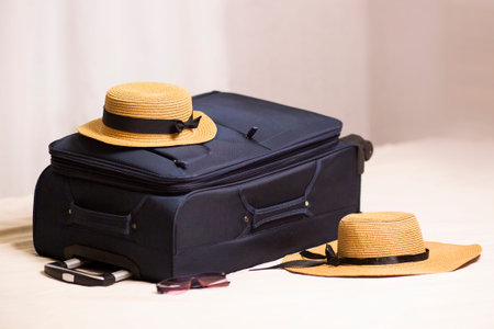 suitcase, travel bag and straw hats lie on the bed in the hotel room. Check-in at the hotel,...