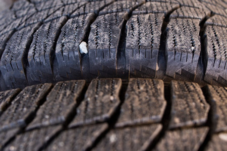 Close-up of grooves on a car tire, stones stuck inside the rubber. Winter wheels after use....