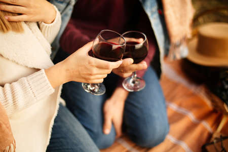 Two glasses of red wine in the hands of young people on a date. Picnic in nature, romantic trip.の写真素材