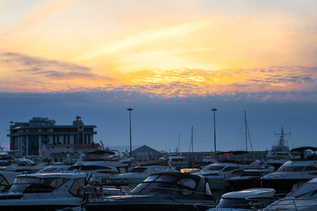 Luxury yachts docked in sea port at sunset. Marine parking of modern motor boats and blue water. Tranquility, relaxation and fashionable vacation.の写真素材