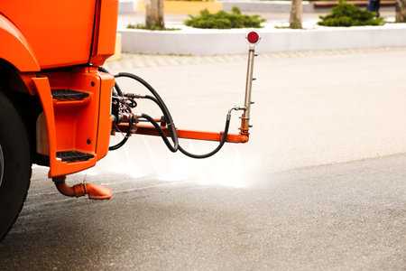 An orange watering machine washes the road
