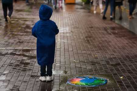A frustrated, stressed child is lost on the street. Scared crying child outside. Childhood violence and unrest. Loneliness, abandoned childrenの写真素材