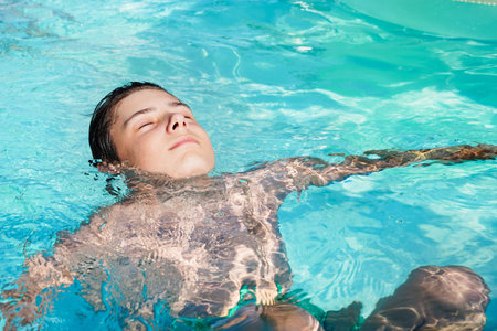 A teenager, a guy swims in the pool on a summer sunny day, the benefits of bathing, swimming and...