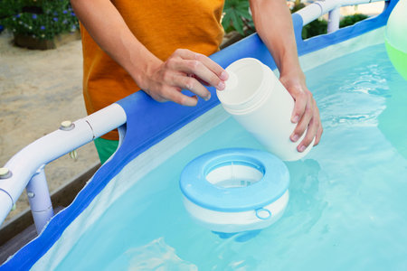White mini chlorine tablet in the hand of a service worker for disinfection of swimming pools. The...