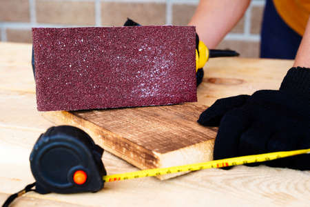 Carpenter worker working with wood, sanding and removing the top layer with a sander. Surface polishing for smoothnessの写真素材