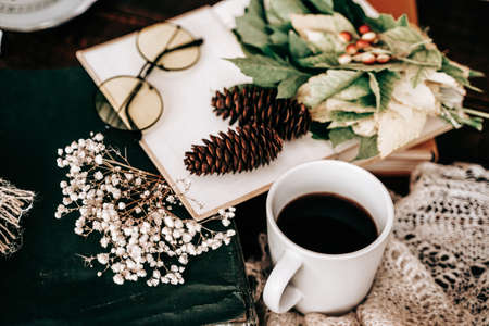 Book with glasses cup and books, maple leaves on wooden table. Side view. Fall seasonの写真素材