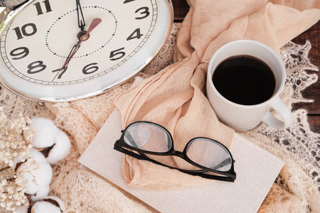 Startup concept. Cup of coffee, alarm clock, books, glasses. Start your day with morning coffee....