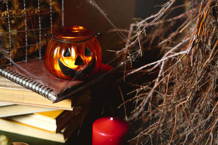 Colorful still life theme for Halloween: scary dark book covered with spider webs, burning pumpkin, candlestick.の写真素材
