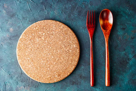 Top view of round cutting board between fork and spoon on rustic table, background for menu, with copy spaceの写真素材