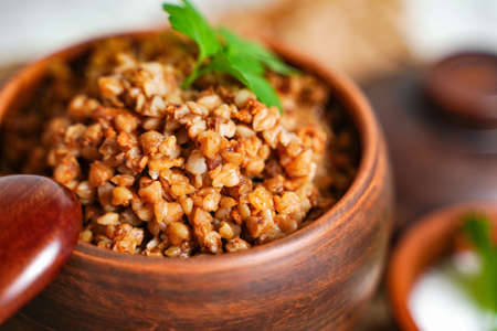 Selective focus on buckwheat porridge close up with parsley in pot - breakfast, healthy food. Close upの写真素材
