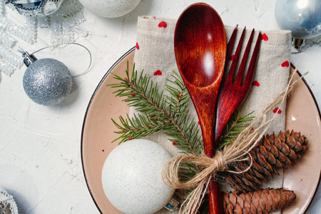 Christmas table setting with decorations, plate, rustic wooden cutlery for a festive dinner