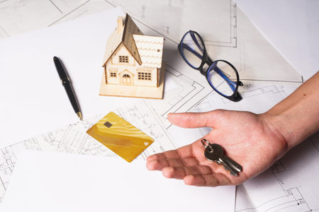 wooden house model on workplace desk with construction worker team hands shaking greeting start up...