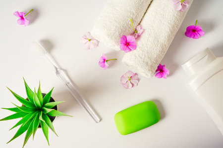 Spa white background pink flowers and a bottle of shampoo, soap white towels rolls. Body care,...