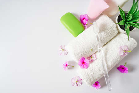 Face and body care products with pink flowers. Freshness and body care. Skin cosmetics. White clear towels for purityの写真素材