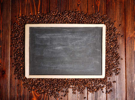 Empty template frame made from coffee beans. Wooden background black board with coffee seeds and copy spaceの写真素材