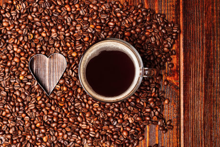 Empty Heart shape made inside of coffee beans background, cup of coffee with espresso drink,...