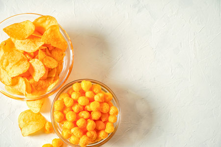Beer snacks, potato chips and spicy corn balls in glass bowls. Copy space for text