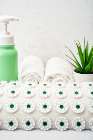 Acupuncture massage pillow with green white microneedles and magnets to improve blood circulation. White towels and moisturizing oil, lotion. Kuznetsov applicator close-up, alternative medicineの写真素材