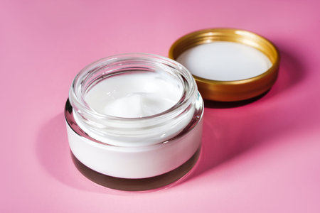 Cosmetic moisturizing anti wrinkle white cream in glass jar on pink background