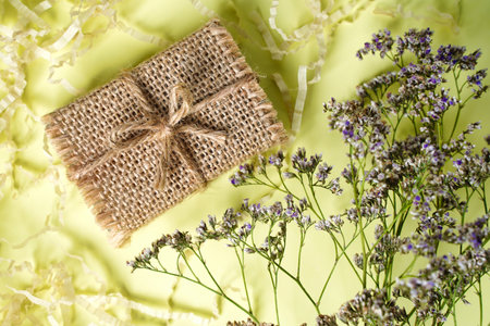 Small craft gift box rustic style on light yellow background with dry flowers