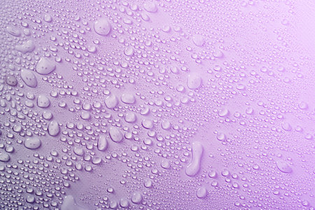 Cosmetics moisturizing liquid drops on a light violet purple pastel background. Hyaluronic acid,...