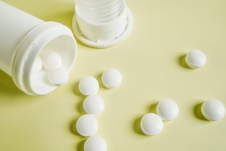close up bottle of pills with medicinal white tablets on yellow background