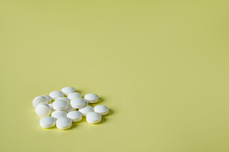 Medicine yellow background from bunch white pills, macro. Drug production backdrop, closeup. Tablet...