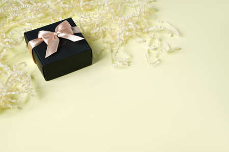 Dark gift present box with ribbon and bow on yellow background top view copy space. Flat lay holiday background. Congratulation for menの写真素材