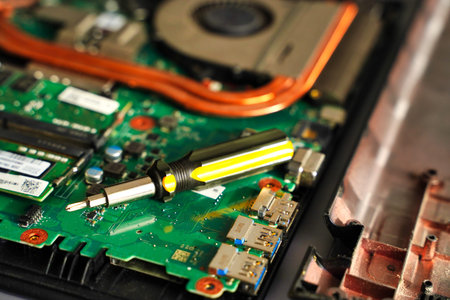 Close up repairing broken laptop notebook computer with a screwdriver