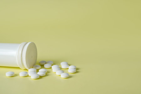 Medicine yellow background from bunch white pills, macro. Drug production backdrop, closeup. Tablet...