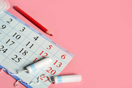Menstruation days products, calendar with red marked dates of menstruation on pink background with copy spaceの写真素材