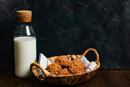 Oatmeal cookies close up view. Stack of homemade delicious rolled oats cookies on table napkin, oat flakes and milk bottle. Morning breakfast table background.の写真素材