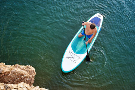 Top view on Paddleboard SUP Man having fun paddle board. Fitness recreational leisure activity. Beach rental equipment on travel vacation.の写真素材