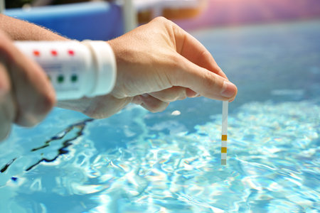 Checking the water quality of a pool with the help of a test strip with PH value, chlorine and...