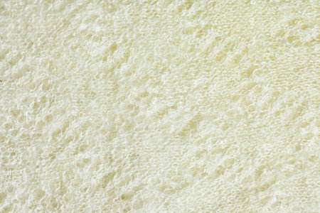 Texture of warm white knitted winter clothes. Background knitted cozy clothes handmade