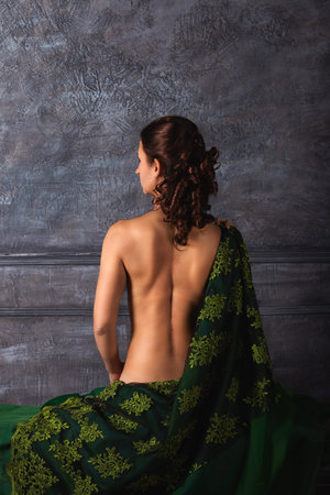 Beautiful, charming young woman posing in renaissance style. Beautiful girl with curls with a naked back. Back viewの写真素材