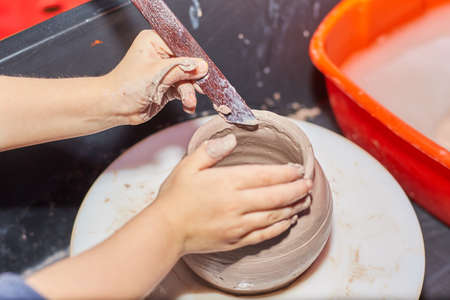 Kid making ceramic pot on pottery wheel. Modeling of clay on a potter's wheel In the pottery workshopの写真素材