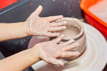 Kid making ceramic pot on pottery wheel. Modeling of clay on a potter's wheel In the pottery workshopの写真素材