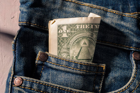 Amarican money Dollar in blue jeans pocket denim background texture.
