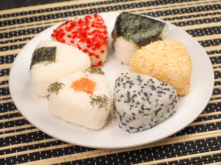 A series of shots of onigiri of various shapes and fillings on a plate. top view. Japanese rice...